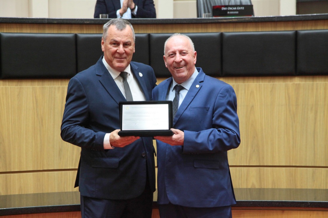 Presidente da entidade que administra o HRAV, Claudio Ropelato, recebe homenagem do deputado Oscar Gutz (PL), proponente da sessão.