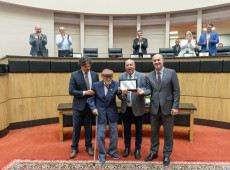 Deputados Marquito, Oscar Gutz e Jos&eacute; Milton Scheffer entregam homenagem a Glauco Olinger.
