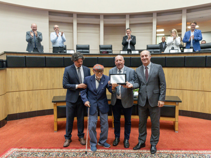 Deputados Marquito, Oscar Gutz e Jos&eacute; Milton Scheffer entregam homenagem a Glauco Olinger.
