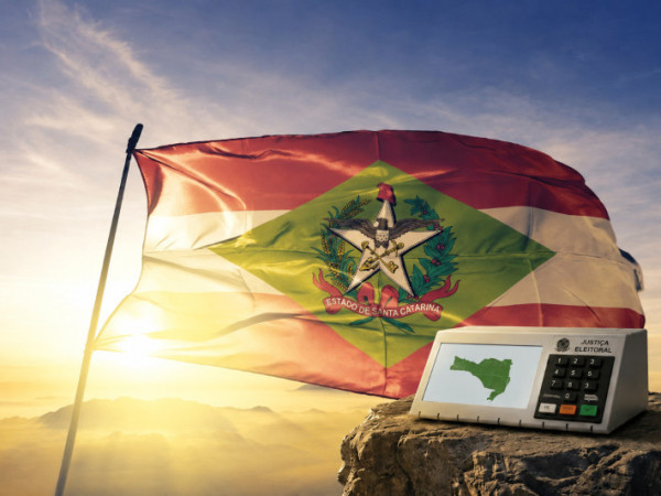 Bandeira de Santa Catarina e urna eletr&ocirc;nica com o mapa do estado